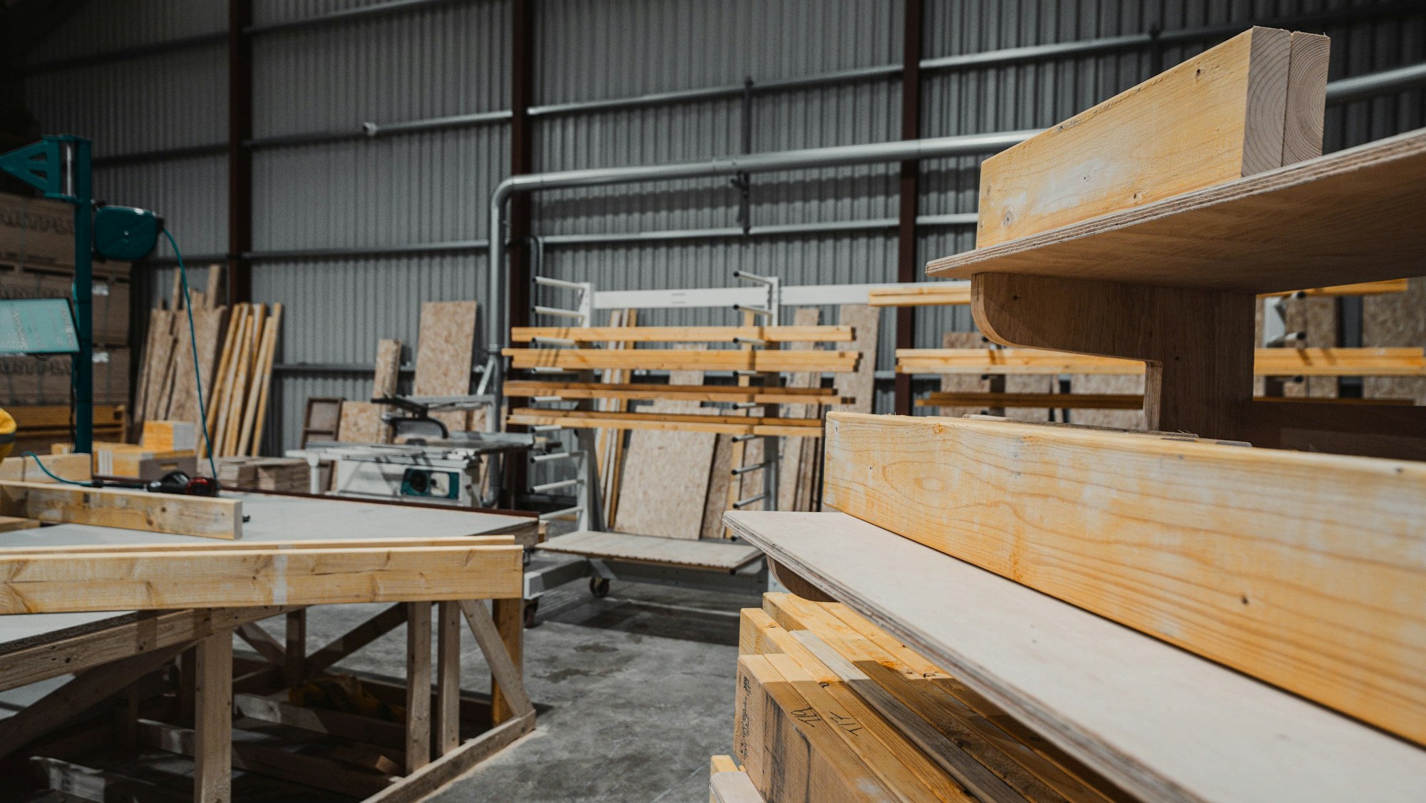 Boards and lengths of timber stacked in the workshop, ready to be cut